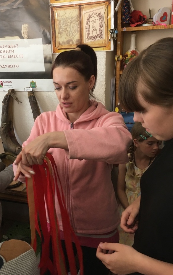 Елена Мишина учит ребят плетению конской уздечки.jpg