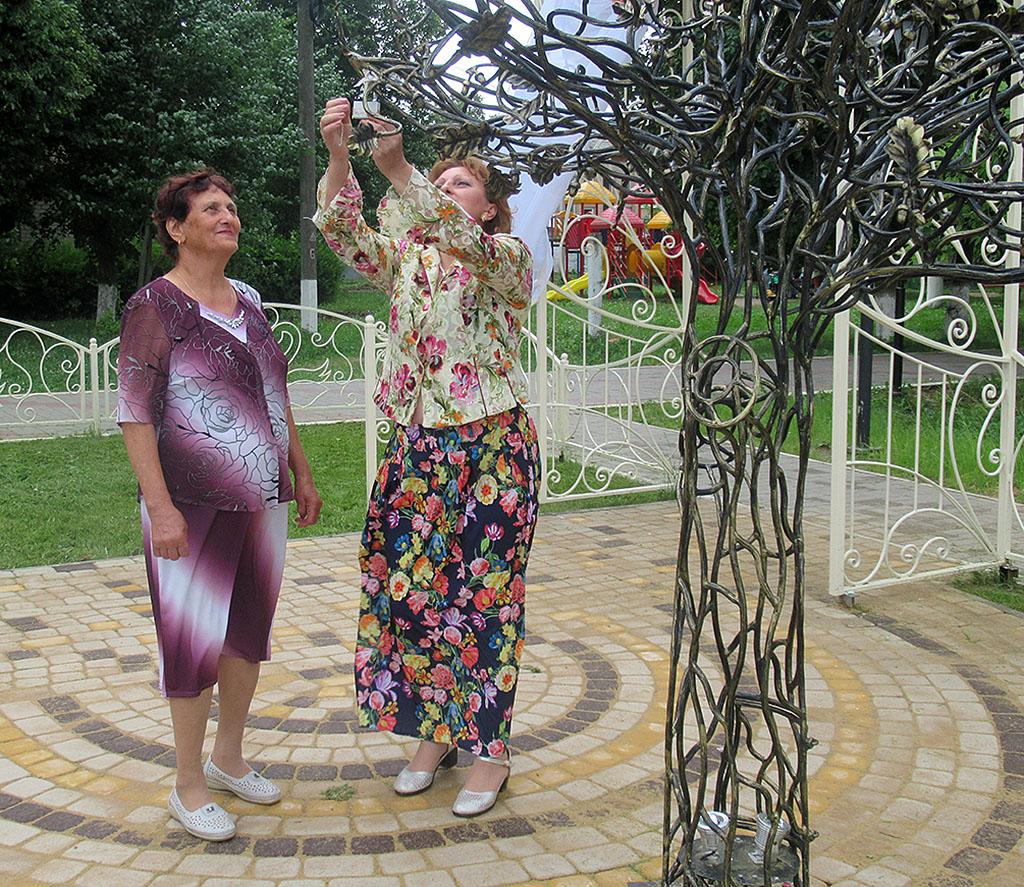 Феодора Стамат с дочерью вешают замочек на дерево счастья.jpg