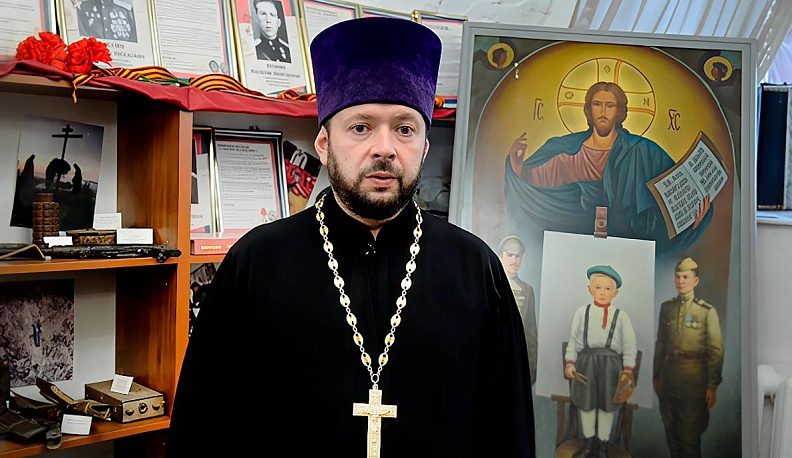 Протоиерей Алексей Пелевин в Музее истории Православия на Калужской земле. На заднем плане – картина художника Алексея Голубева «Память о войне (дед, отец и я)», которую он подарил музею.